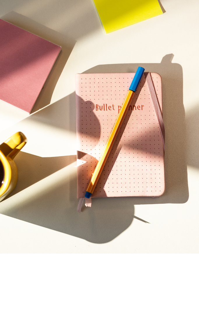 Picture of journal, pens at a desk 